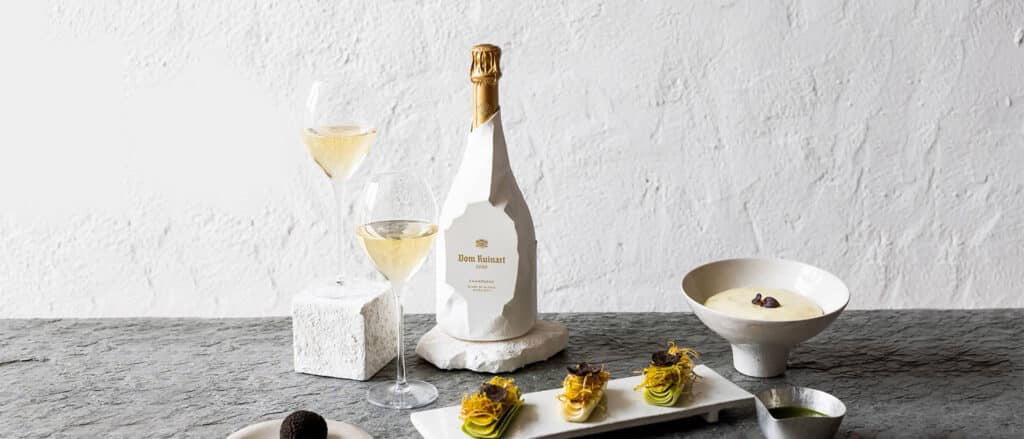 Bottle of Dom Ruinart Blanc de Blancs 2013 Champagne with elegant glassware, showcasing its golden hue and fine bubbles