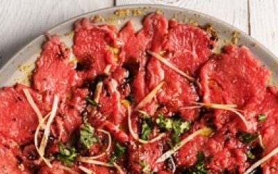 Carpaccio of beef on a plate with mustard and spices
